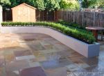 New lawn, planting, shed and fence patio was constructed using fossil sandstone in 4 sizes laid to a random pattern with a curved block planter wall painted in gun ship grey and planted with a topiary hedge.