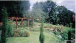 Curved timber Arbour built leading to Timber arch bridge over water feature