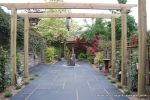 Small town house garden with a Japanese feel black limestone random paving installed with a centre slate water feature, Timber arbour constructed and garden planted with feature plants  