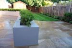 AFTER: New lawn and planting new fence and shed patio was constructed useing fossil sandstone in 4 sizes laid to a random pattern with a curved block planter wall painted in gun ship grey and planted with a topiary hedge.  