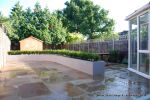 AFTER: New lawn and planting new fence and shed patio was constructed useing fossil sandstone in 4 sizes laid to a random pattern with a curved block planter wall painted in gun ship grey and planted with a topiary hedge.  