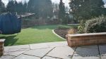 New sandstone patio installed with inset water feature with stepping stones across it, patio retaining wall constructed and new sweeping lawn edged with red brick leading to octagon sandstone patio 