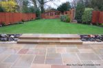 Patio installed with 4 size sawn sandstone paving edged with firestone rocks and alpine planting, steps built with sawn sandstone uprights and sawn sandstone bullnose treads