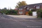 Driveway constructed using pewter grey paving with contrasting colour band and feature curved double row of kerbs with Topiary hedge to retain level change & inset LED lights