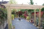 Small town house garden with a Japanese feel black limestone random paving installed with a centre slate water feature, Timber arbour constructed and garden planted with feature plants  